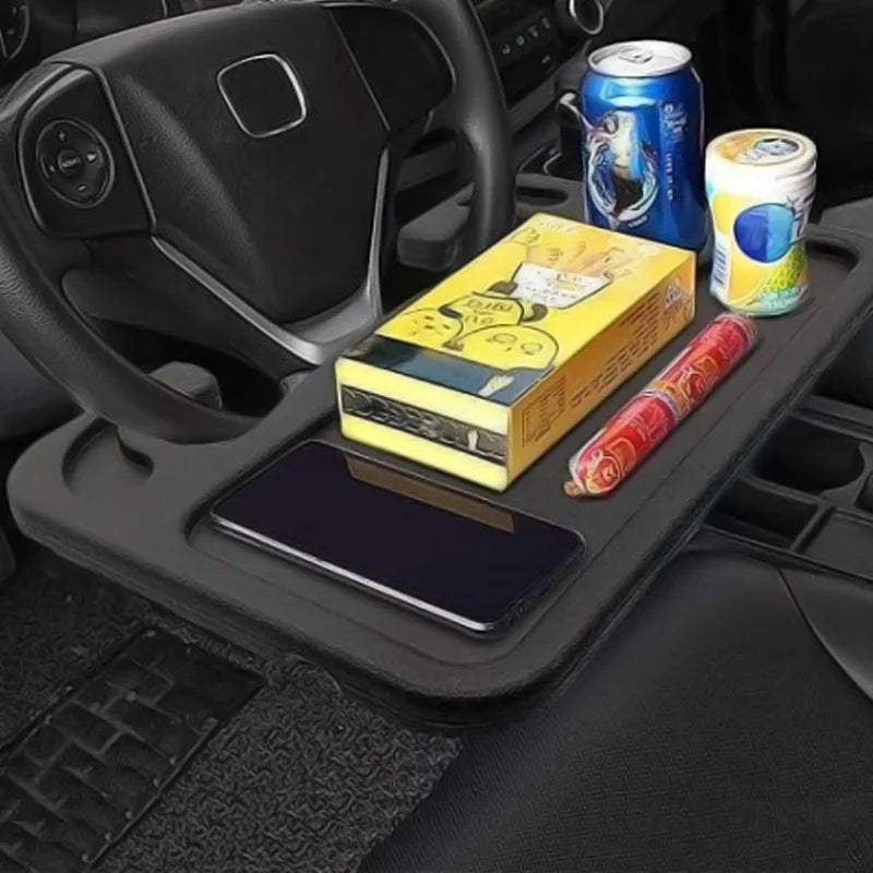Une tablette de voiture fixée au volant, utilisée comme espace de rangement pour des objets personnels, boissons et snacks.